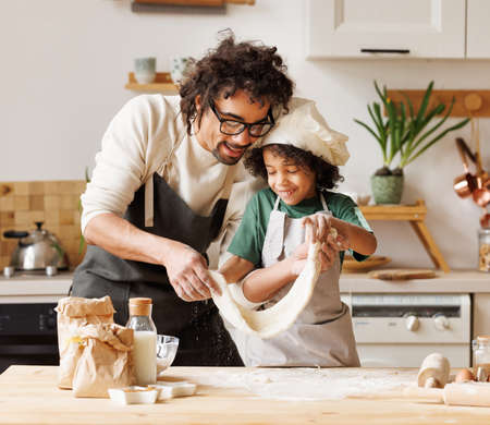 Happy black father and son preparing dough togetherの写真素材