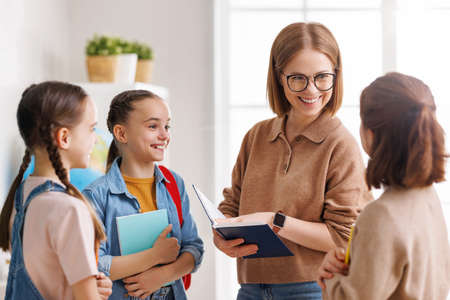 Teacher speaking with students during lesson in sunlit classroomの写真素材
