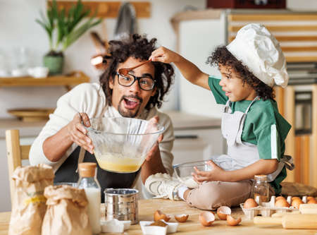 Black father and child making batter in kitchenの写真素材