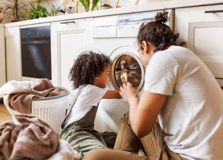 Son helping dad to load washing machineの写真素材