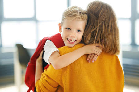 Cheerful child boy hugs mom before the first day of schoolの写真素材