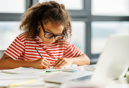 Smart ethnic girl making notes during online lessonの写真素材