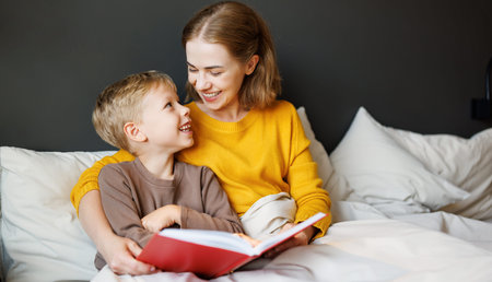 Happy mother and son reading book together on bed