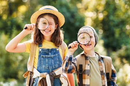 cheerful happy kids with magnifying glass studies the environment in summer in nature