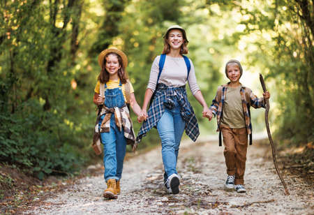 happy family mother and children with backpacks went hiking in forestの写真素材
