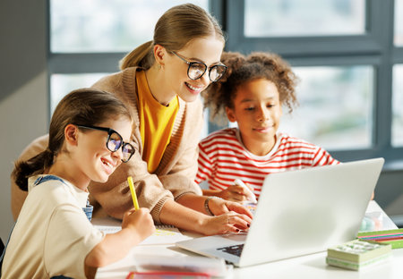 Teacher and pupils using laptop in school