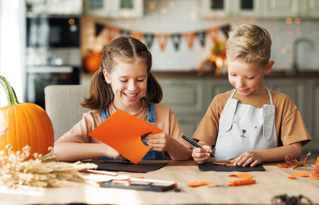 Happy children brother and sister smiling and making Halloween home decorations togetherの写真素材