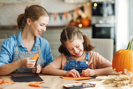 Happy smiling family mother and daughter making Halloween home decorations togetherの写真素材