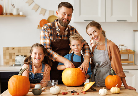 Happy family mother, father and kids to remove pulp from from pumpkin while carving jack o lantern with familyの写真素材