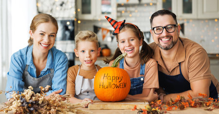 Happy family mother, father and children with pumpkin during celebration, preparing home Halloween decorationsの写真素材