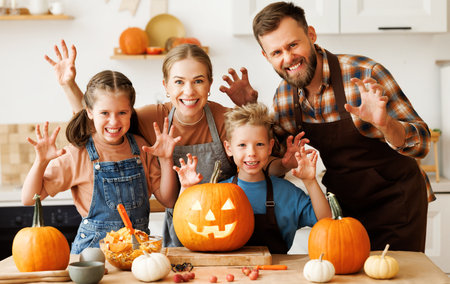 Happy family mother, father and kids scary gesture, while make jack-o-lantern from pumpkin, getting ready for halloweenの写真素材
