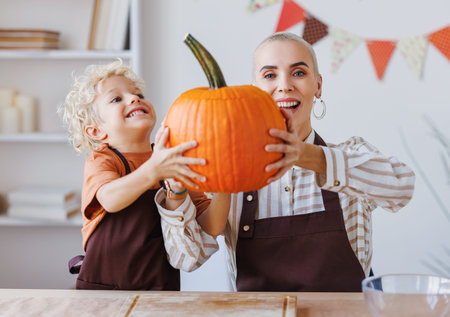 Son and mom making Jack-o-Lantern together at home, carving Halloween pumpkinの写真素材
