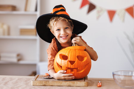Smiling kid boy laughs and holding pumpkin Jack-o-lantern with during Halloween celebrationの写真素材