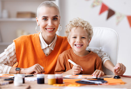 Young family mother and child preparing decorations for Halloween and engage in creativityの写真素材
