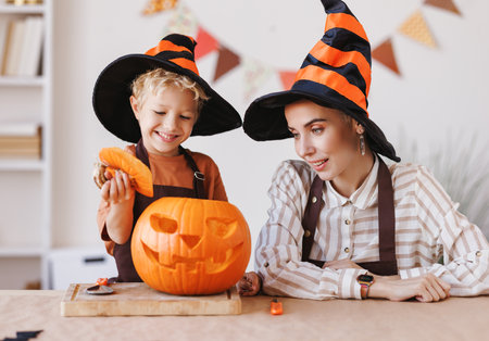 Son and mom making Jack-o-Lantern together at home, carving Halloween pumpkinの写真素材
