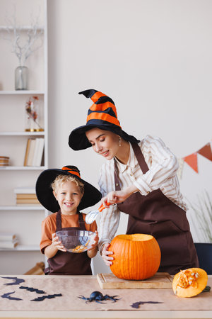 Son and mom making Jack-o-Lantern together at home, carving Halloween pumpkinの写真素材