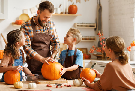 Son and dad making Jack-o-Lantern together at home, carving Halloween pumpkinの写真素材