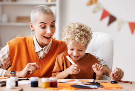 Young family mother and child preparing decorations for Halloween and engage in creativityの写真素材
