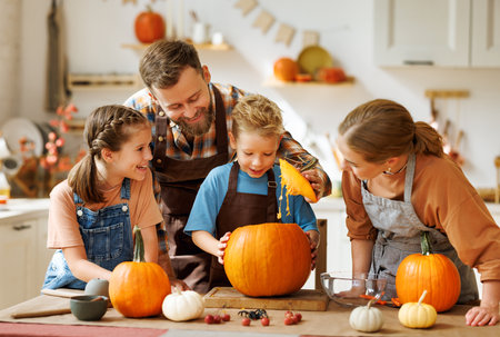 Happy family mother, father and kids to remove pulp from from pumpkin while carving jack o lantern with familyの写真素材