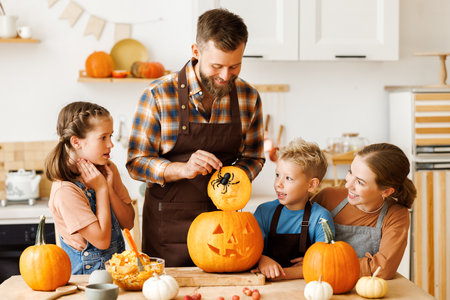 Happy family mother, father and kids to remove pulp from from pumpkin while carving jack o lantern with familyの写真素材
