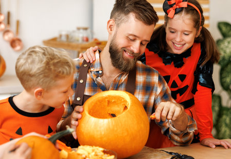 Children and dad making Jack-o-Lantern together at home, carving Halloween pumpkinの写真素材