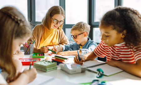 Teacher helping children with schoolwork at schoolの写真素材