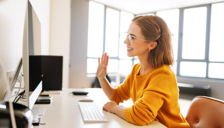 Happy young female having video call while working remotely or studying online on computer from homeの写真素材