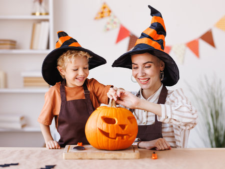 Son and mom making Jack-o-Lantern together at home, carving Halloween pumpkinの写真素材