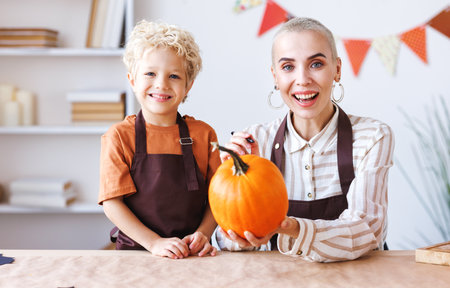 Son and mom making Jack-o-Lantern together at home, painting Halloween pumpkinの写真素材