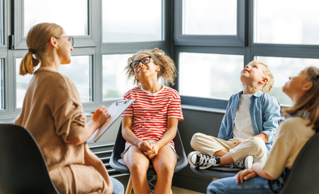 School psychologist with a group of school children conducts a mental health lesson, group therapy, a psychotherapy session in a bright officeの写真素材