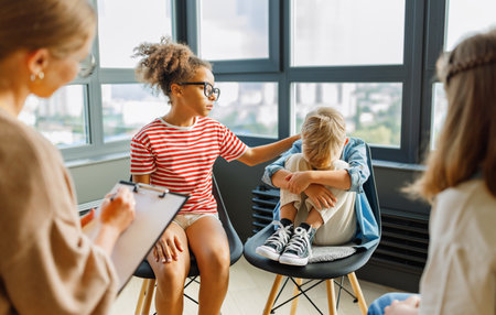 School psychologist with a group of school children conducts a mental health lesson, group therapy, a psychotherapy session in a bright officeの写真素材