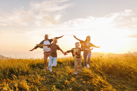 Happy family: mother, father, children son and daughter running back on nature on sunsetの写真素材