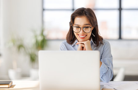 beautiful young smiling woman working remotely behind a laptop at homeの写真素材