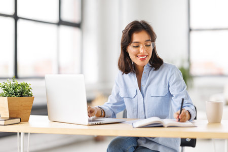 beautiful young smiling woman working remotely behind a laptop at homeの写真素材