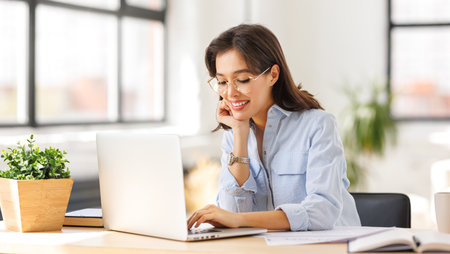 beautiful young smiling woman working remotely behind a laptop at homeの写真素材