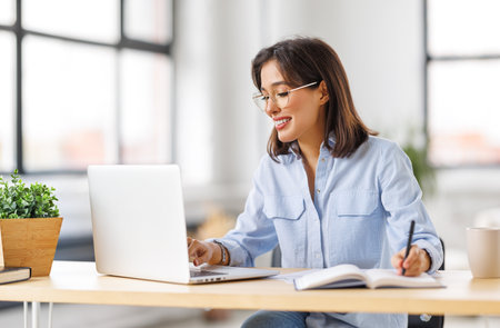 beautiful young smiling woman working remotely behind a laptop at homeの写真素材