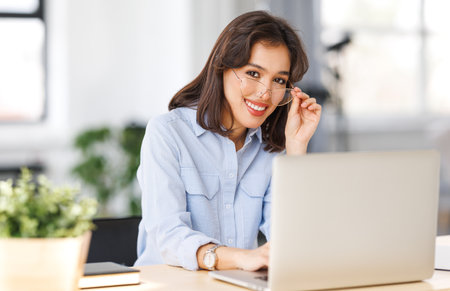 beautiful young smiling woman working remotely behind a laptop at homeの写真素材