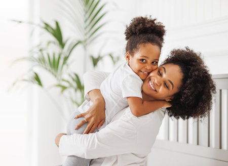 happy ethnic family. African american mother and daughter play and laugh in bed an homeの写真素材