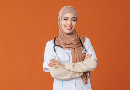 Professional woman doctor in muslim national hijab isolated on orange backgroundの写真素材