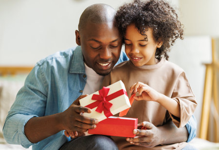 happy fathers day. African american kid son giving gift box to her dad for holiday at homeの写真素材