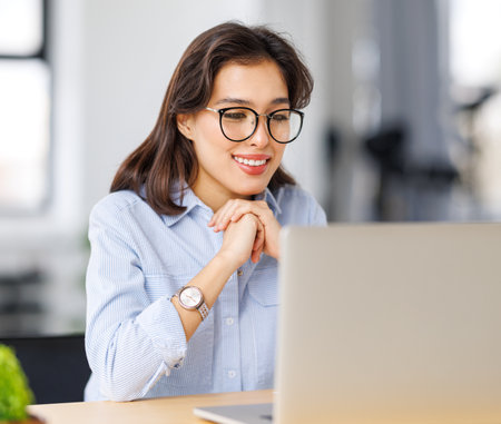 beautiful young smiling woman working remotely behind a laptop at homeの写真素材