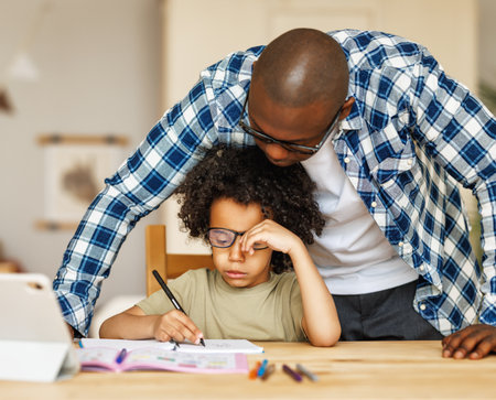 African american father helps son to do homework at homeの写真素材