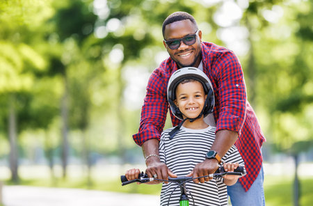 Portrait of happy family father teaches boy son to ride bike in park in natureの写真素材