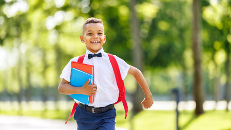 cheerful african american boy schoolboy runs with a briefcase down the streetの写真素材