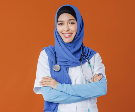 Professional woman doctor in muslim national hijab isolated on orange backgroundの写真素材