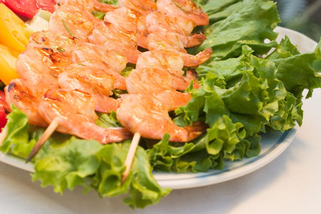 Grilled shrimps on wood sticks served with tomatos and green sald are ready to eatの写真素材