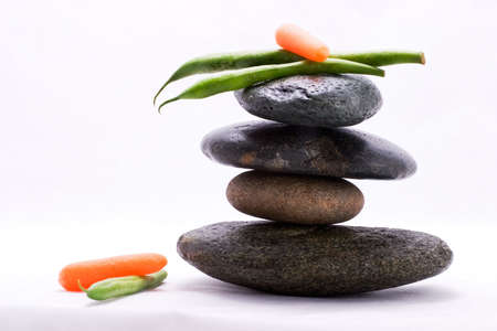 Pods of green beans and  carrot on the top of zen stones pyramid in balanceの写真素材