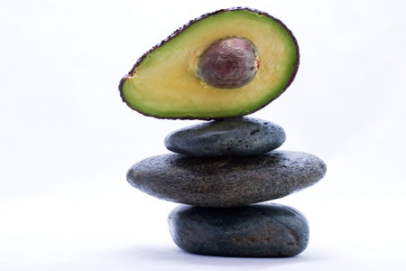 Half cut avocado on the top of zen stones pyramid in balance
