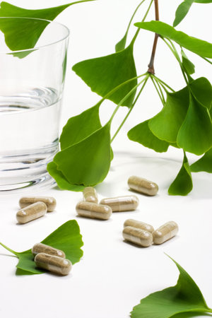 Ginkgo Biloba extract pills and fresh Ginkgo Biloba leaves with glass of water best suited for aged people alternative medicine adsの写真素材