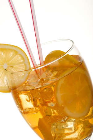 Single tall glass of iced tea full of ice cubes, slices of lemon and two straws over white backgroundの写真素材
